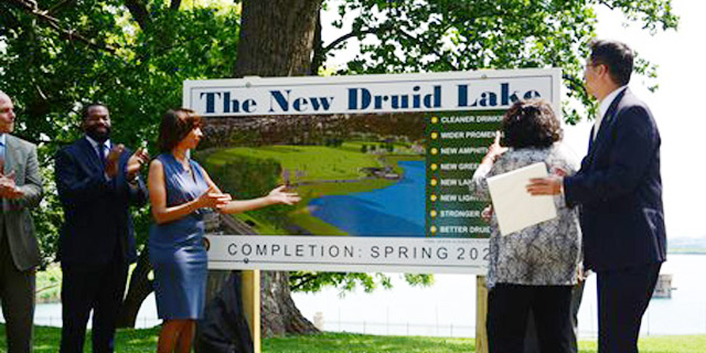 The Mayor and team looking at the New Druid Lake Project sign at the lake.